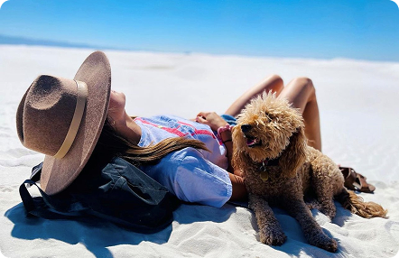 Nurse relaxing with a dog on white sands