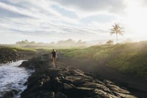 A woman is walking on lava rocks near the ocean, Big Island, Hawaii.