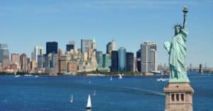 Statue Of Liberty By Cityscape Against Blue Sky