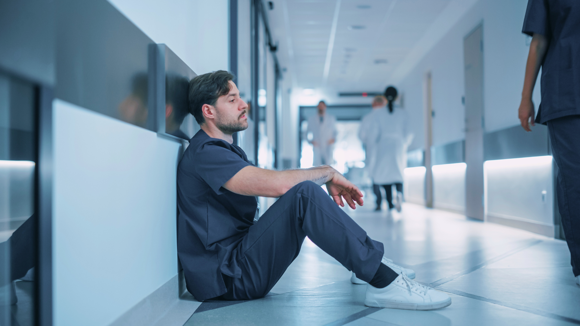 clinician sitting stoically on floor representing low mental health in healthcare