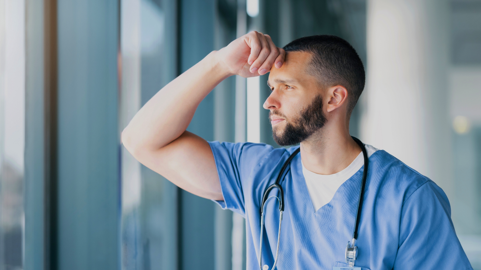 Male nurse looking gazing out a window