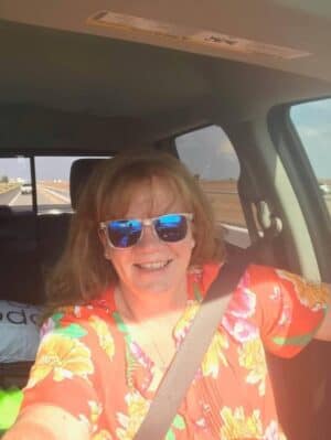 image of leigh anne wearing orange shirt in a car as a passenger