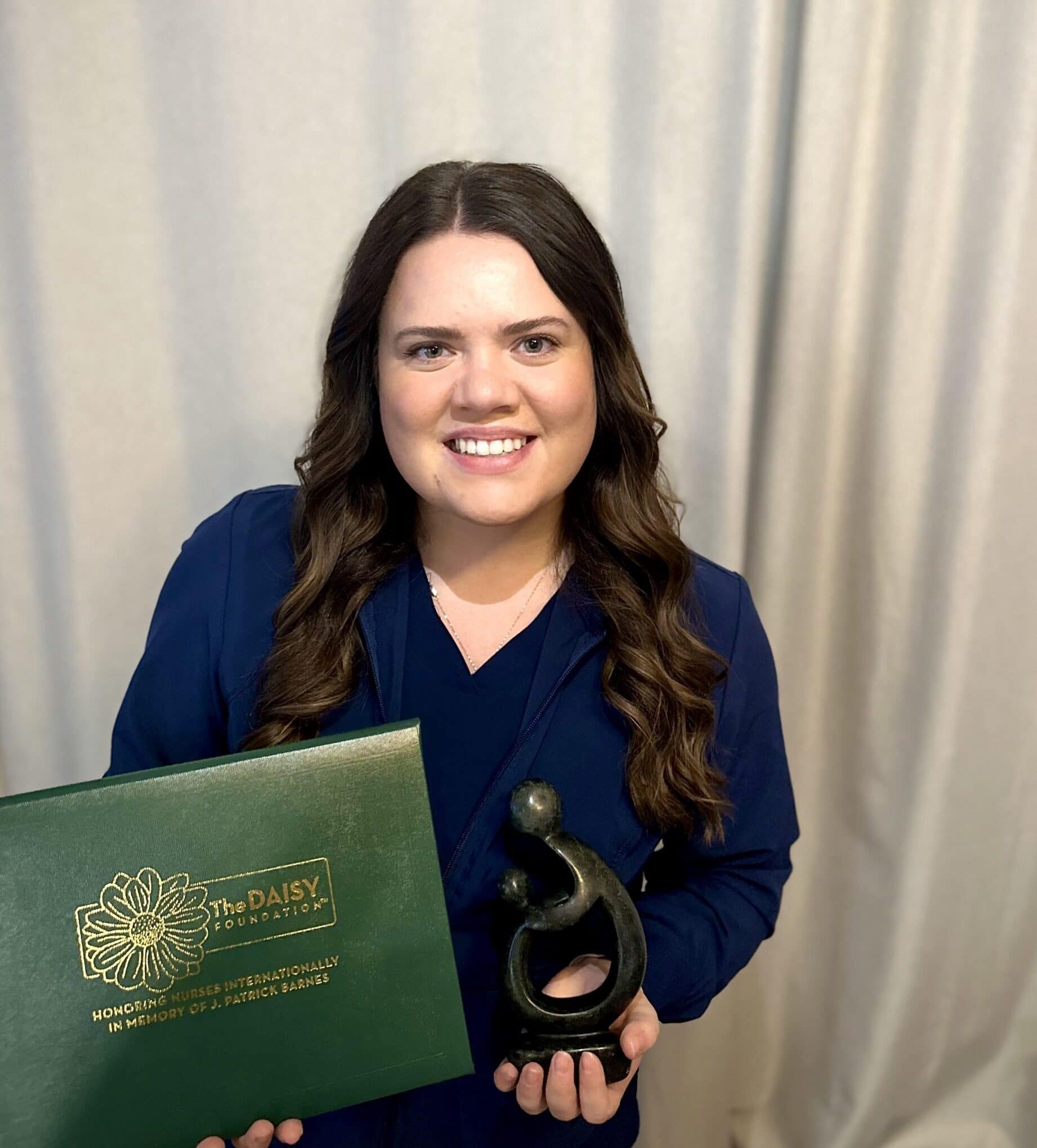 nurse with brown hair holding DAISY award