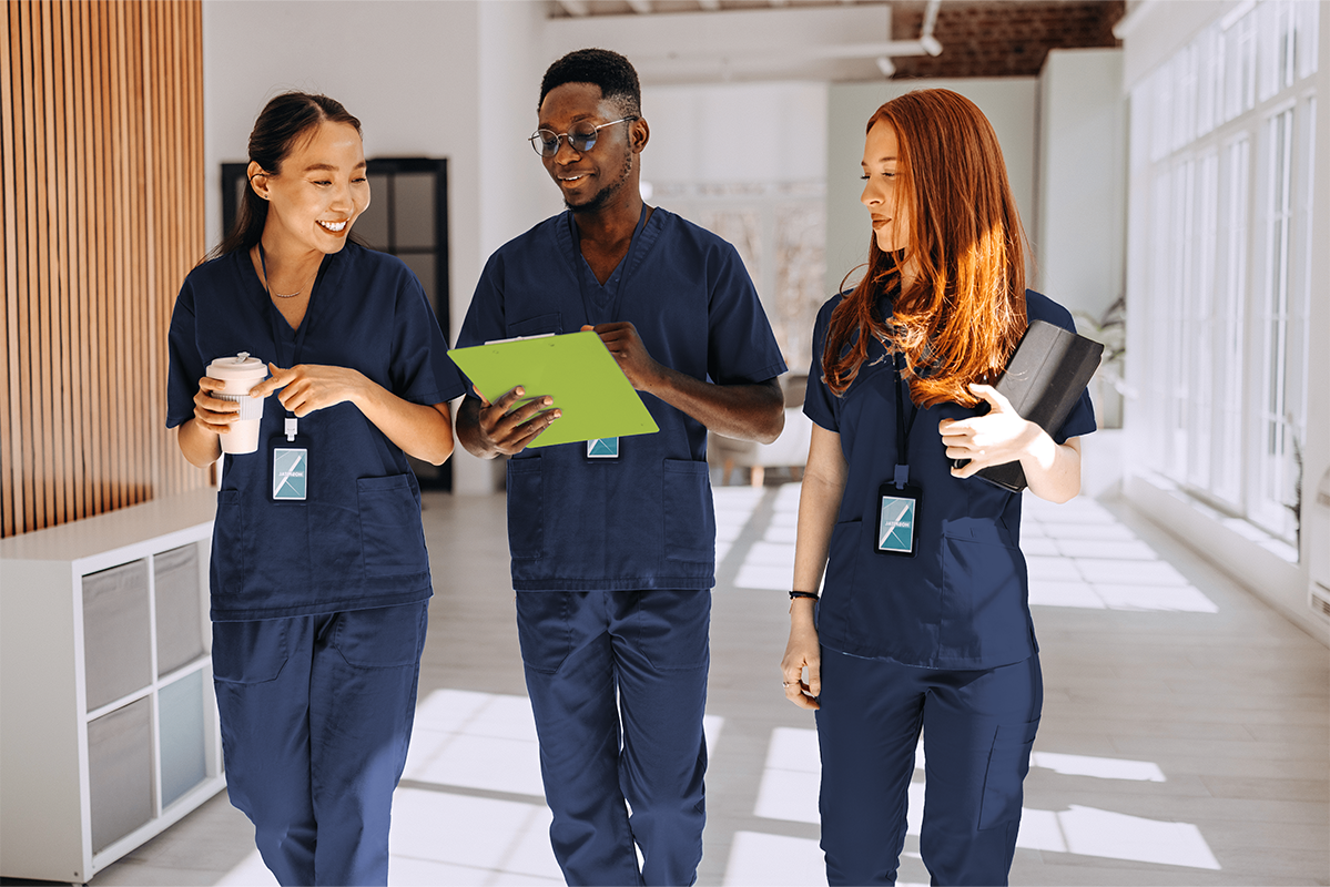 three nurses in navy blue scrubs walking down hospital hallways