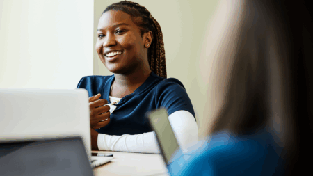 nurse in dark blue scrubs on laptop smiling
