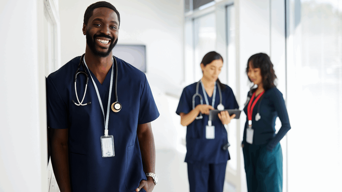 one-clinician-in-the-foreground-smiling-and-two-clinicians-in-the-background-talking