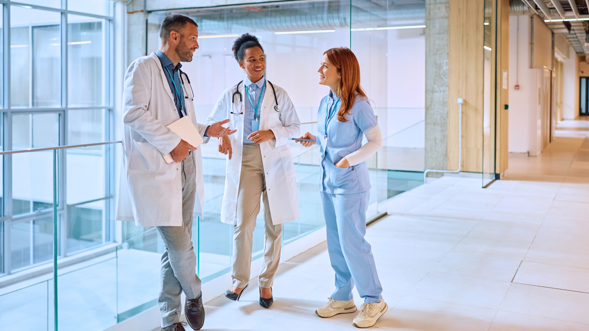 A female nurse talking to two doctors in the hall