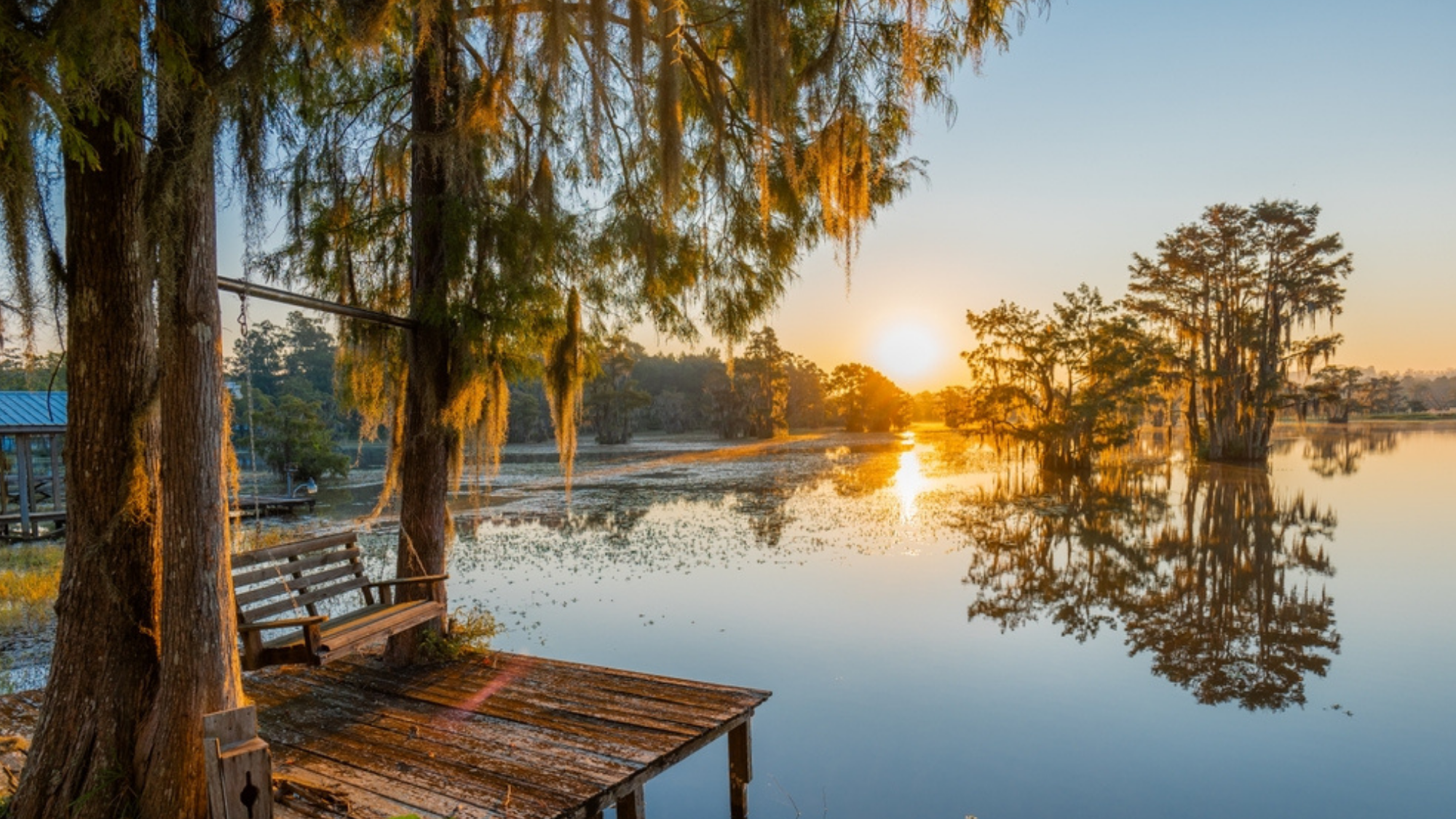 Scenic view of a lake and dock surrounded by trees during sunset in Alabama.